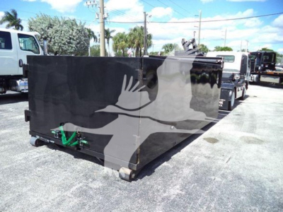 Isuzu NPR-HD box truck bed in a lot with other trucks visible; large black rectangular cargo container on wheels.
