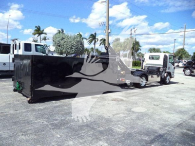 Isuzu NPR HD truck with hooklift equipment and attached flatbed trailer in a lot.