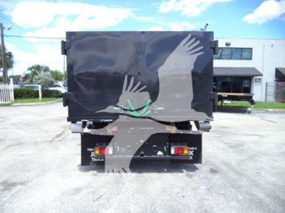 Rear view of a Isuzu NPR-HD hooklift truck with a black tarp cover over the cargo area, bumper lights, and dual rear wheels visible.