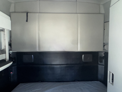 Kenworth T680 sleeper cab interior cargo area showing rear wall and storage panels.