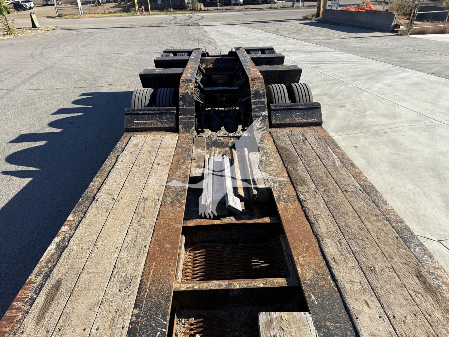 Trailer chassis with fifth-wheel connection showing rusted steel frame and dual axle setup behind the hitch area.
