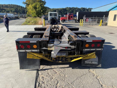 Trailer hitch and rear of 2020 Trail King TK110Hdg lowboy trailer showing dual rear 'Trail King' mudflaps, hazard stripes, and rear lighting assembly.