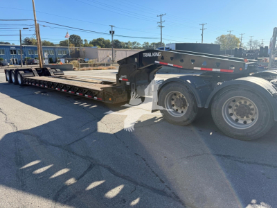 Trail King TK110Hdg lowboy trailer showing long flatbed with black frame, dual rear axles, and wheel wells; visible text includes TRAIL KING on the gooseneck area.