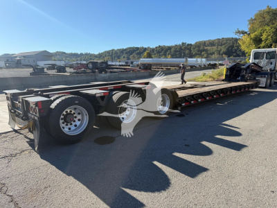 Lowboy trailer with multiple axles showing TK110HDG model; side rails and ramps visible; text on trailer not legible.