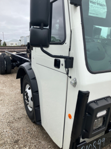 Truck cab close-up showing white exterior, black mirrors, and door area of a Mack LR64 chassis cab.