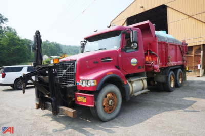 Dump truck with red cab and dump bed showing front bumper, wheel arches, and hydraulic lift in a yard.