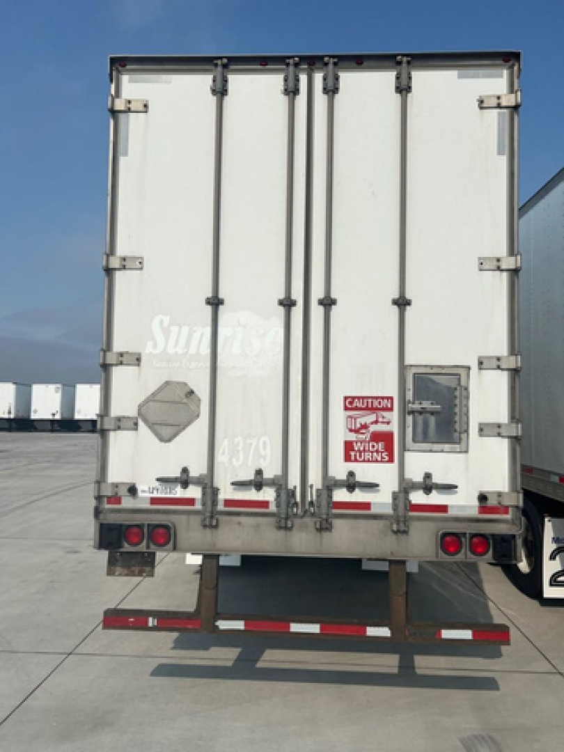 Rear view of a white utility van trailer showing doors, hinges, taillights, and reflective markings.