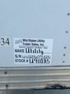 Sticker on side of trailer with VIN 1UYVS2536EP818234, S/N UYVS2536EP818234, Stock U91085, label reading Mid-States Utility Trailer Sales, Inc. Make Utility, locations Sioux City, Sioux Falls, Des Moines, Omaha.