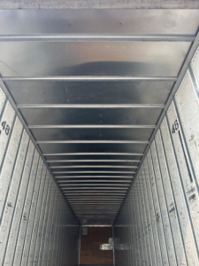 Vertical trailer interior photo showing metal walls with numbered side rails, perspective toward far end.