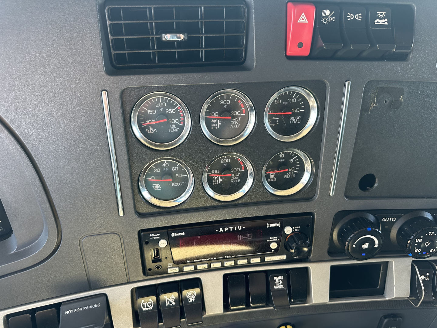 Kenworth T680 dashboard gauges and controls with six analog gauges, vent, and radio panel visible.