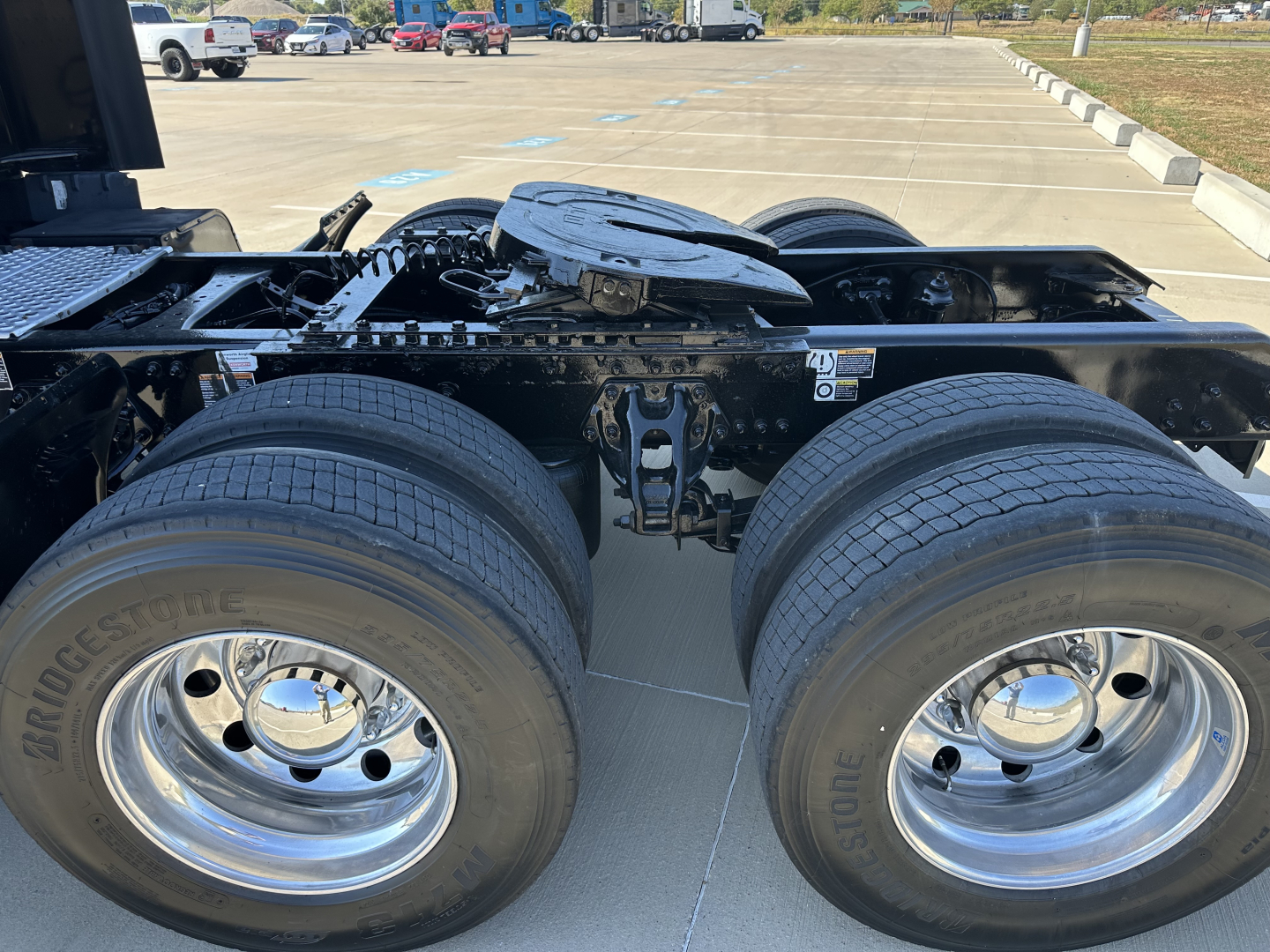 Kenworth T680 wheel area showing dual rear axles and fuel/tractor frame components.