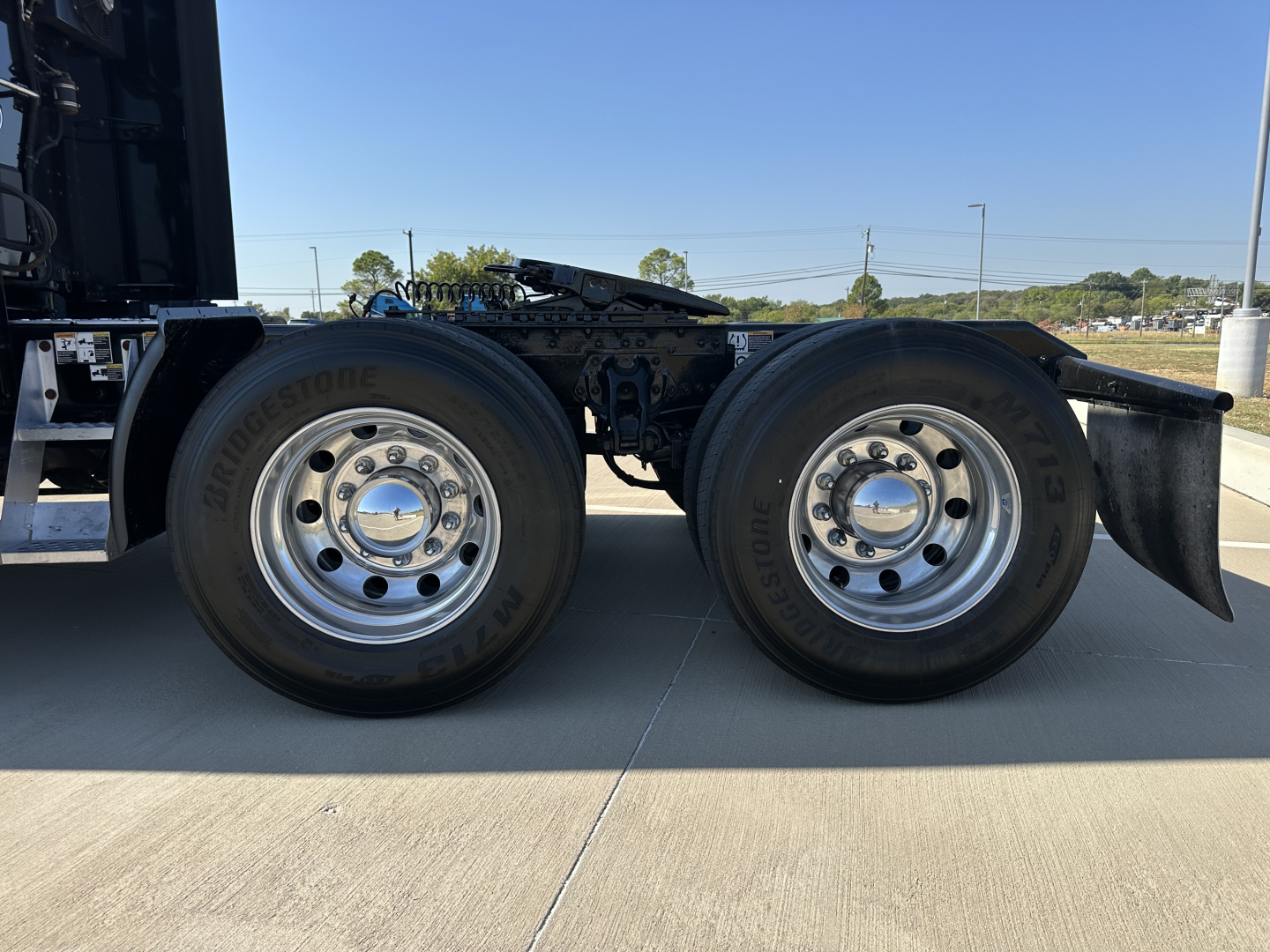 Kenworth T680 drivetrain side view showing dual rear wheels with Bridgestone tires and chrome wheel hubs.