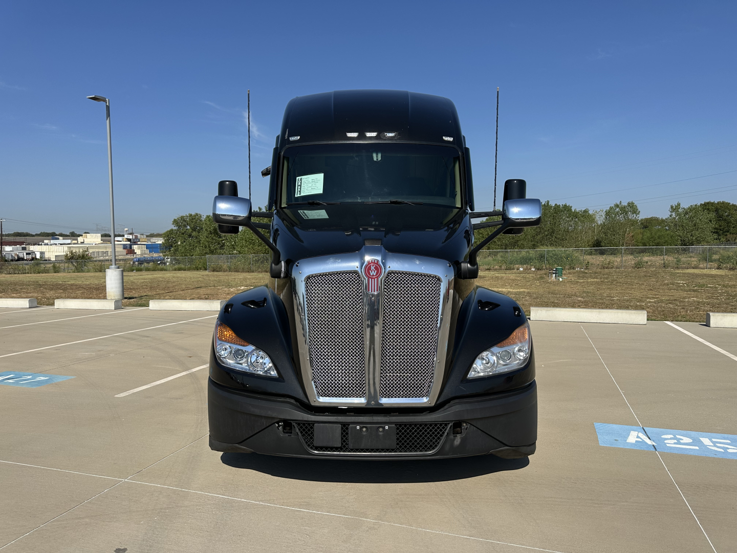 Kenworth T680 front view showing large chrome grille, headlights, and black hood.