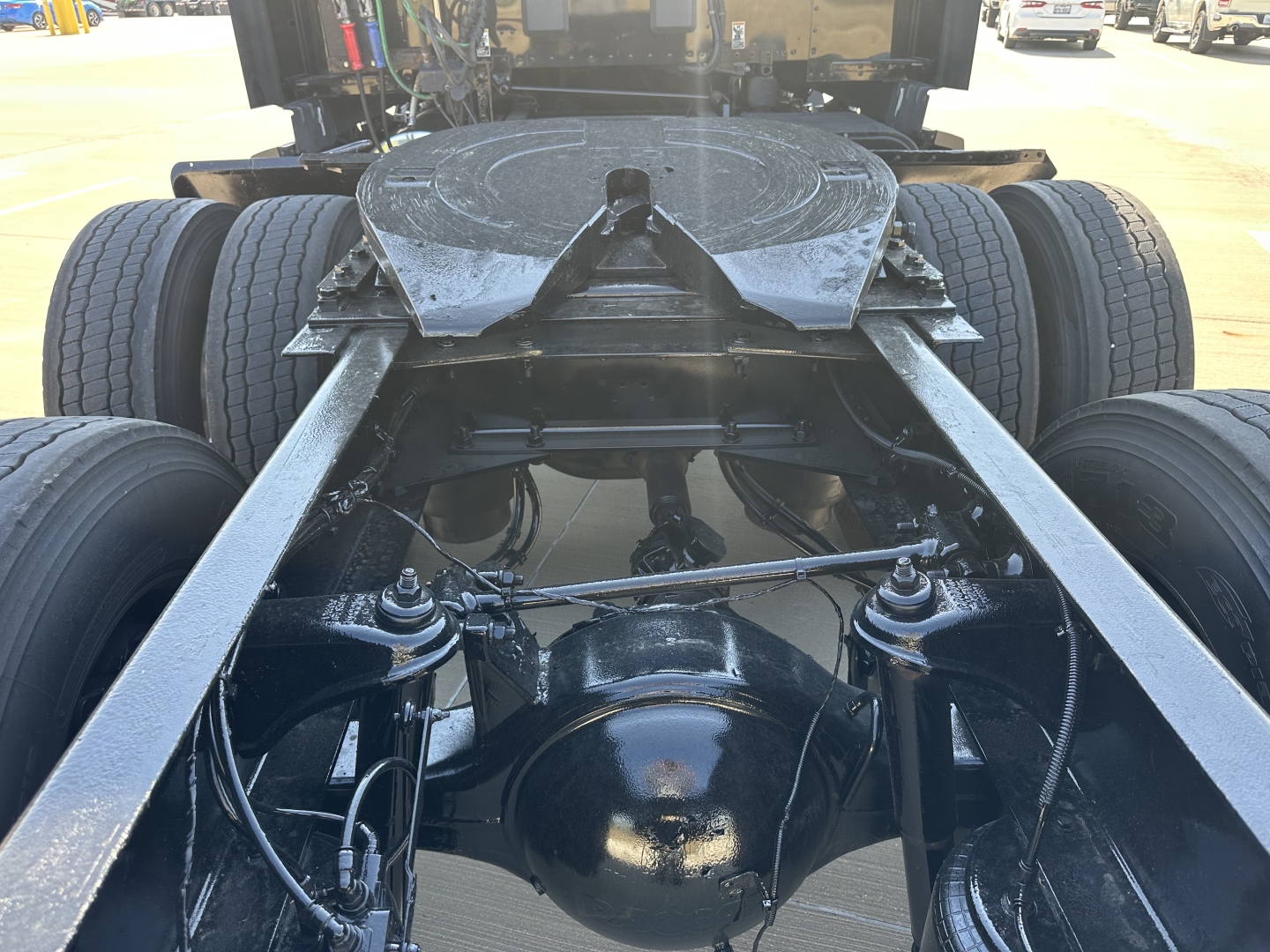 Kenworth T680 rear view showing fifth wheel hitch and dual rear axles with drive housing and suspension components visible.