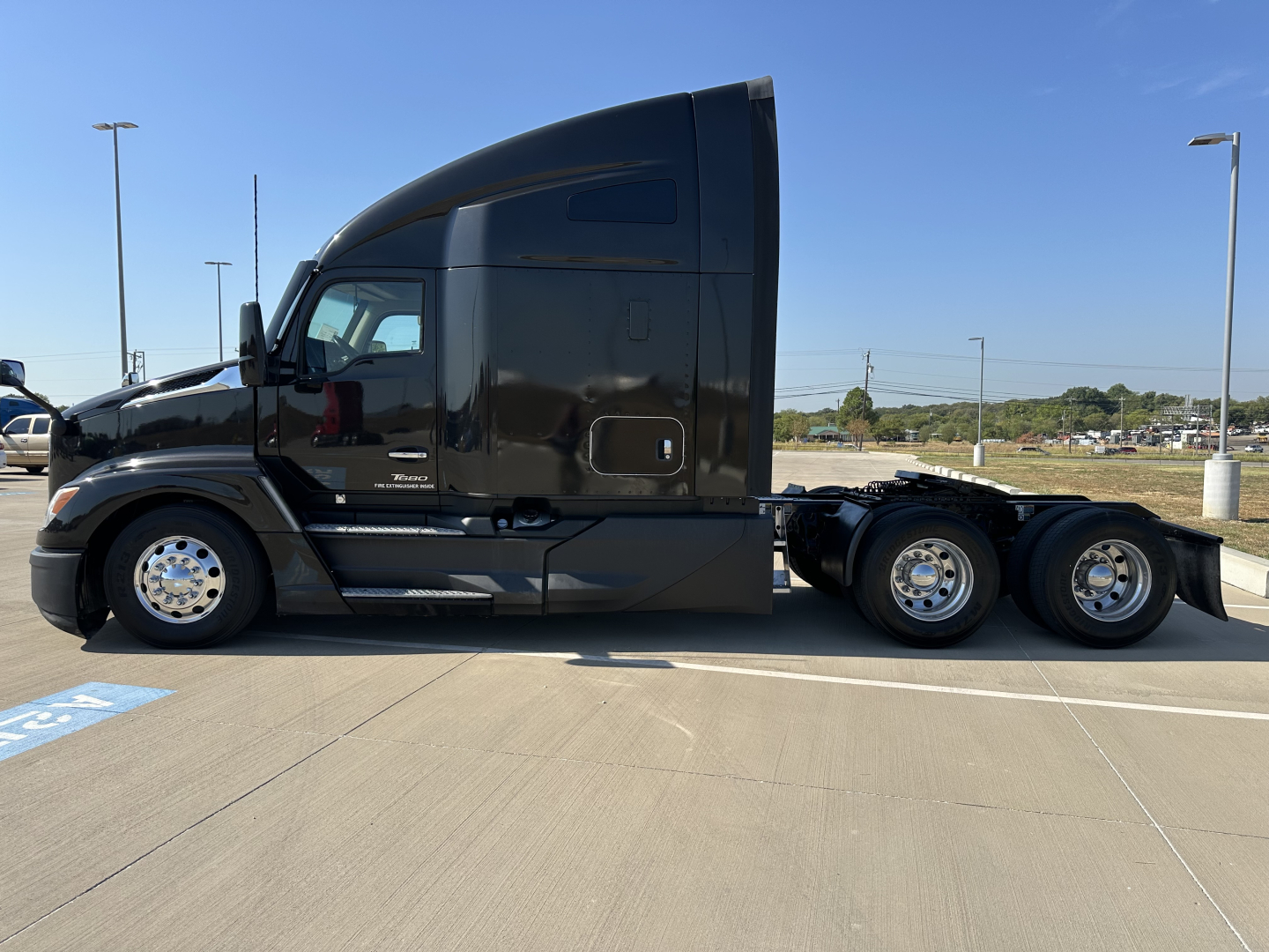 Kenworth T680 semi-truck side profile showing sleeper cab and dual rear axles in a parking lot.