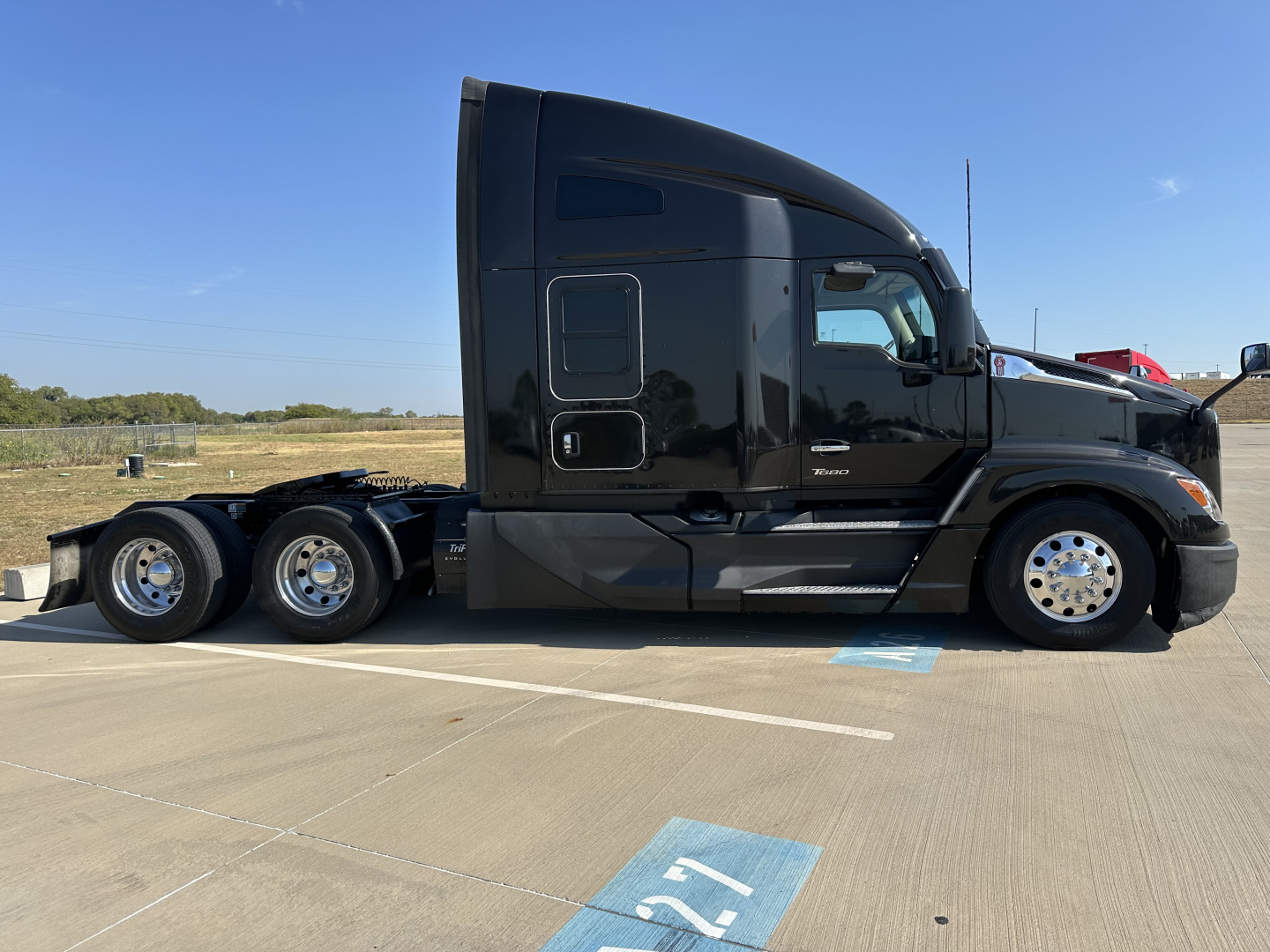 Kenworth T680 tractor side view showing black cab and three rear axles, no visible text labels or stickers.