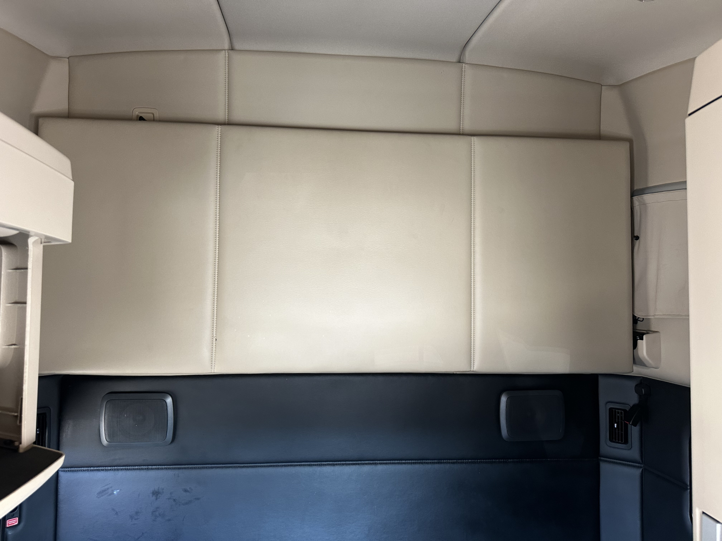 Kenworth truck cabin interior showing sleeper area with light beige panels and dark blue lower trim.