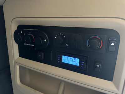 Kenworth T680 HVAC dash with climate controls, digital radio display, and knobs visible in sleeper cab area.