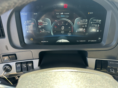 Kenworth T680 cab interior dashboard display showing digital gauges and steering wheel view.