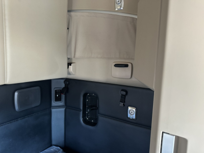 Interior of a Kenworth truck cab showing light beige upper panel and dark lower panel with control module, latch, and wiring in the sleeper area.