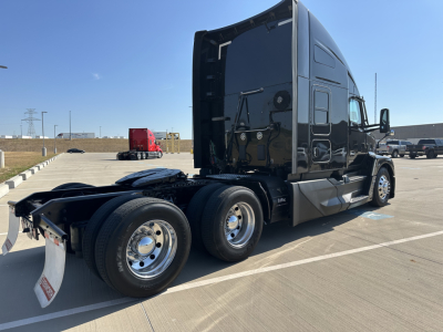 Kenworth T680 tractor rear and side view showing dual rear axles, black glossy cab, fifth-wheel area, and chrome wheels.