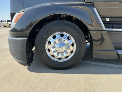Wheel and front fender of a 2022 Kenworth T680 truck showing chrome hub, Bridgestone tire with model G3R tag, and part of black body panel.