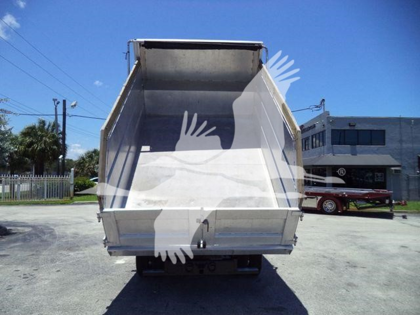 Isuzu NPR-HD dump truck rear view with empty steel bed and open tailgate.