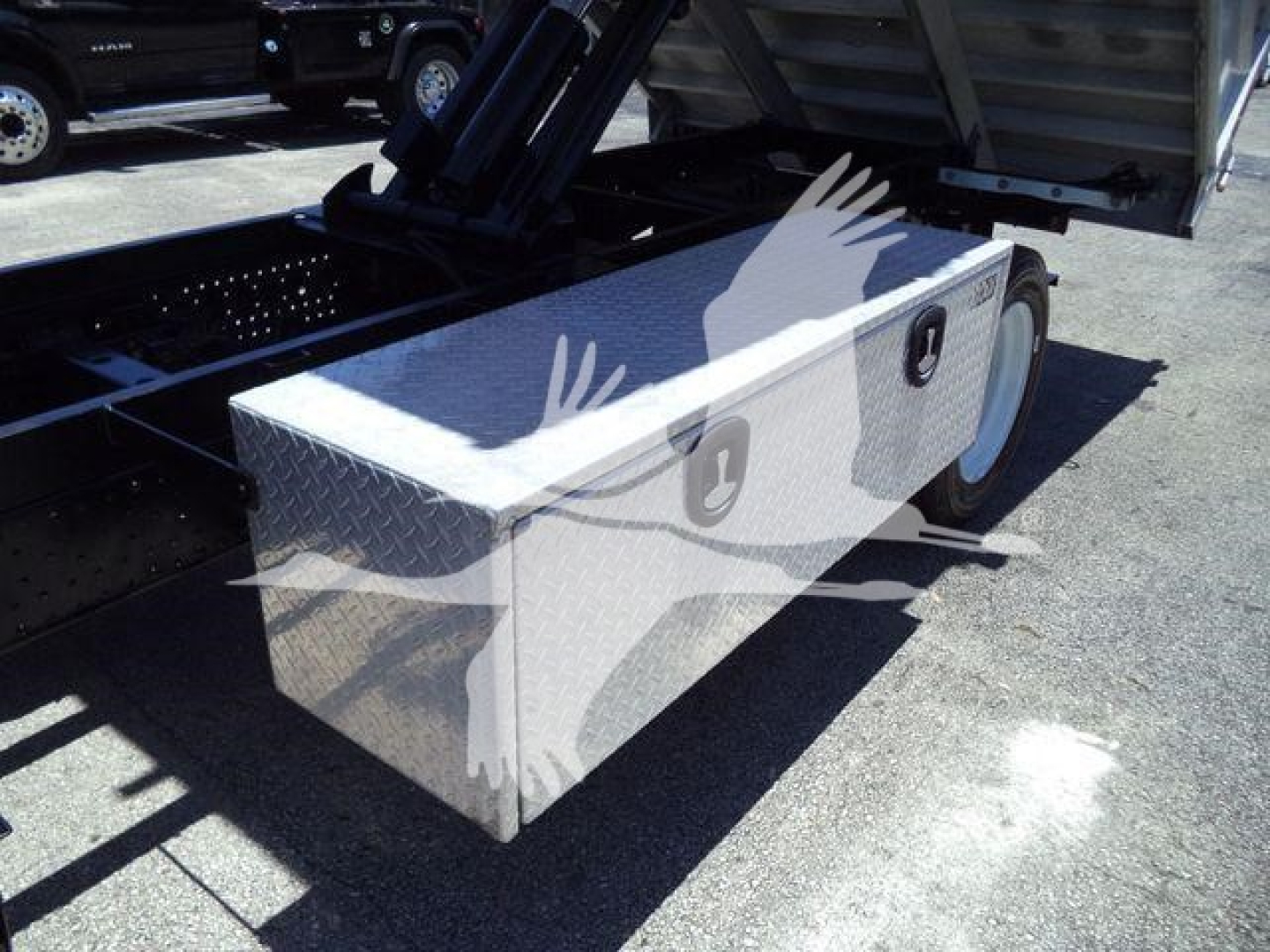 Isuzu NPR HD dump truck component showing a diamond plate aluminum storage box mounted near the wheel, with reflective surface.
