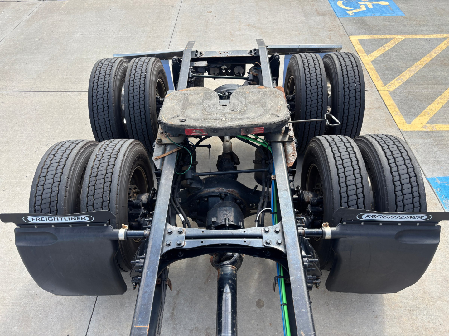 Freightliner truck chassis view showing dual rear axles and fifth wheel area with tires and suspension components.
