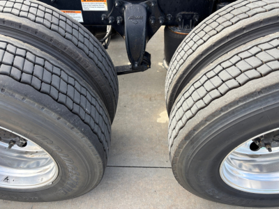 Dual rear tractor tires and hitch assembly of a Freightliner truck chassis, showing dual wheel rims and suspension components.