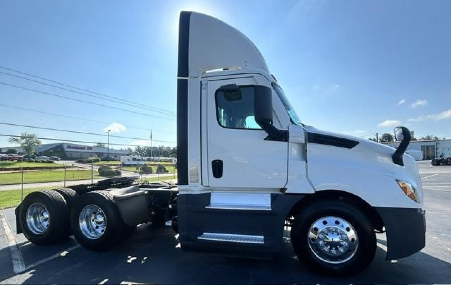 Freightliner Cascadia 126 day cab truck side profile showing white cab, aerodynamic sleeper fairing, dual rear axles, chrome wheels, and large side mirror.