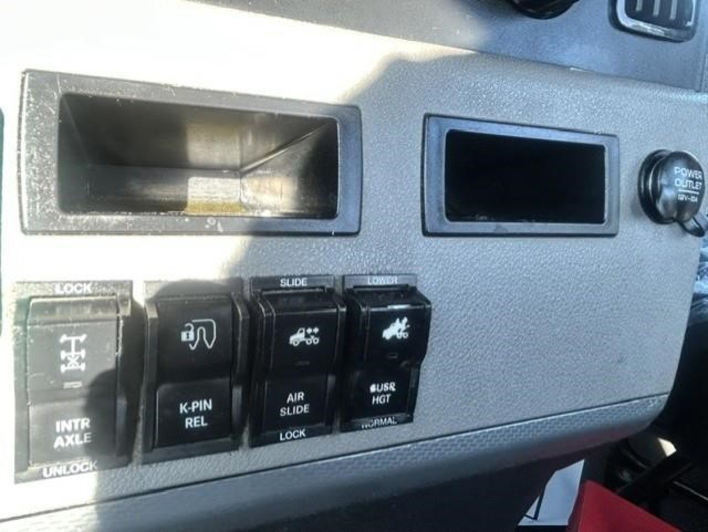 Freightliner Cascadia dash switches including lock, intra-axle, tilt, air slide, and low/high control panels with labeled buttons.