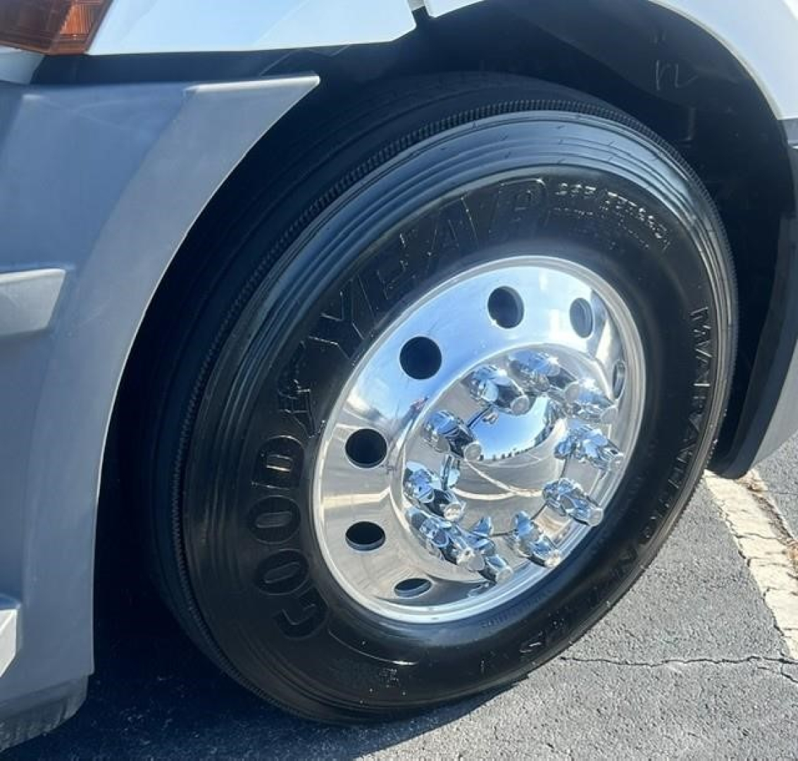 Front wheel of a Freightliner Cascadia 126 truck showing Goodyear tire and chrome hubcap, with partial fender and wheel well.
