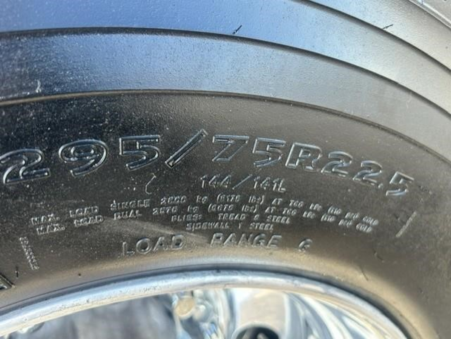Tire sidewall visible with size inscription 295/75R22.5 and load range L7; part of heavy truck wheel