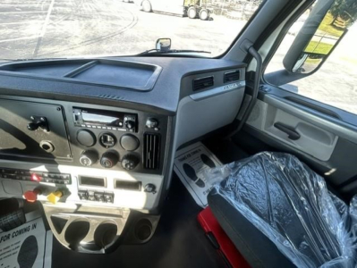 Freightliner Cascadia 126 cab interior showing dash controls and steering wheel with plastic seat cover.
