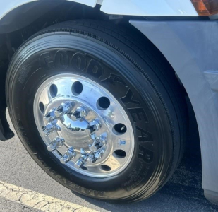 Truck wheel and tire on a Freightliner Cascadia 126 front fender showing Goodyear tire and chrome hubcap.