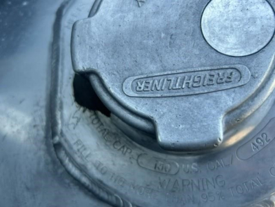 Cascadia 126 fuel cap and surrounding area with FerCHthuriler? label on cap in metal., showing fuel cap with molded text and warning embossed around edge.