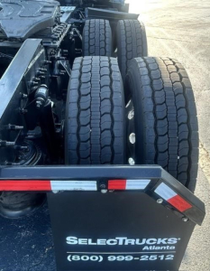 Rear view of Freightliner Cascadia 126 truck showing dual rear axles, tires, and a metal fender with reflective tape and SelectTrucks Atlantе logo.