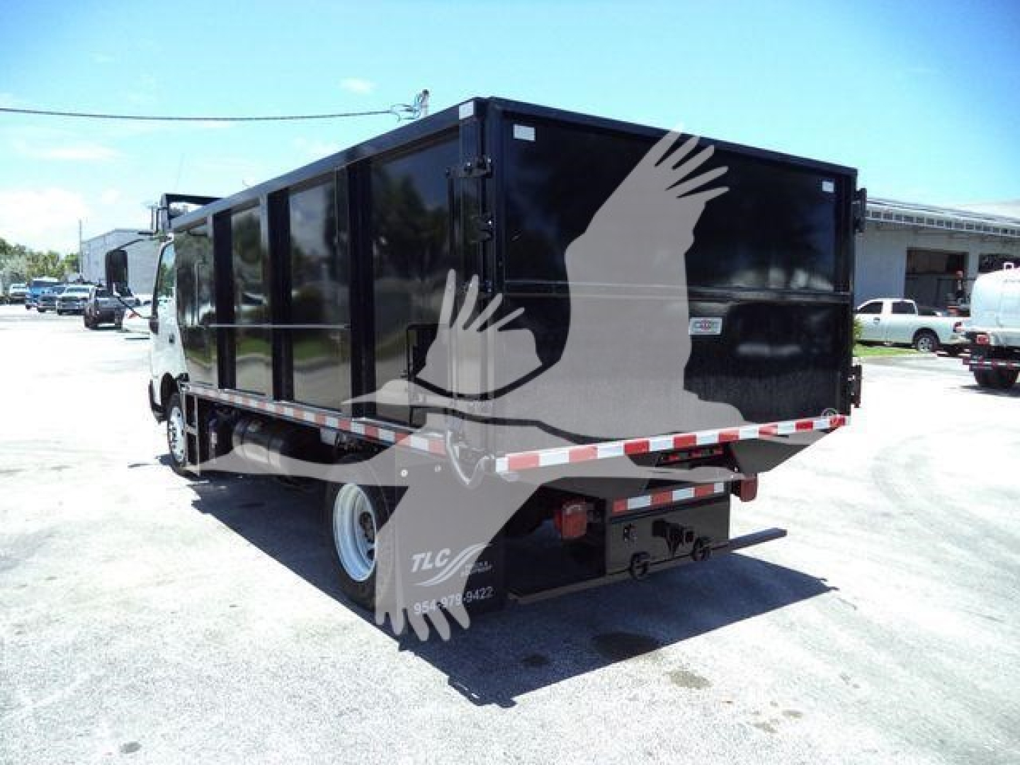 Dump truck with black cargo box and rear-view showing reflective tape and tires; side and rear views visible