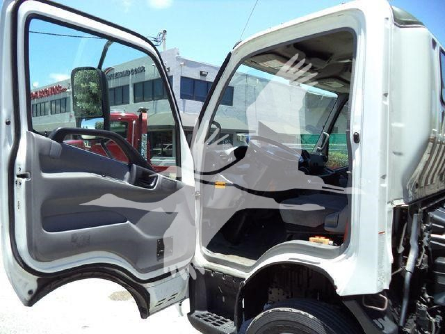 Cab view of a 2020 Hino 195 dump truck with open driver and passenger doors, showing seating and steering wheel.