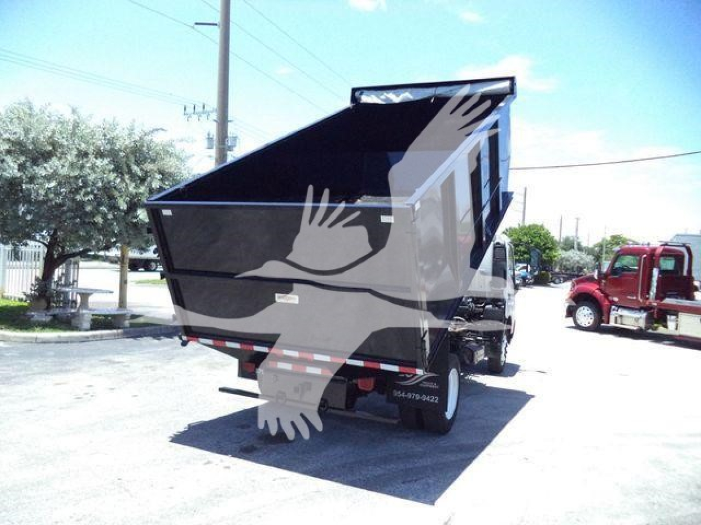 Dump truck rear and side view showing 2020 Hino 195 dump bed in raised position, with wheel and rear taillights visible.