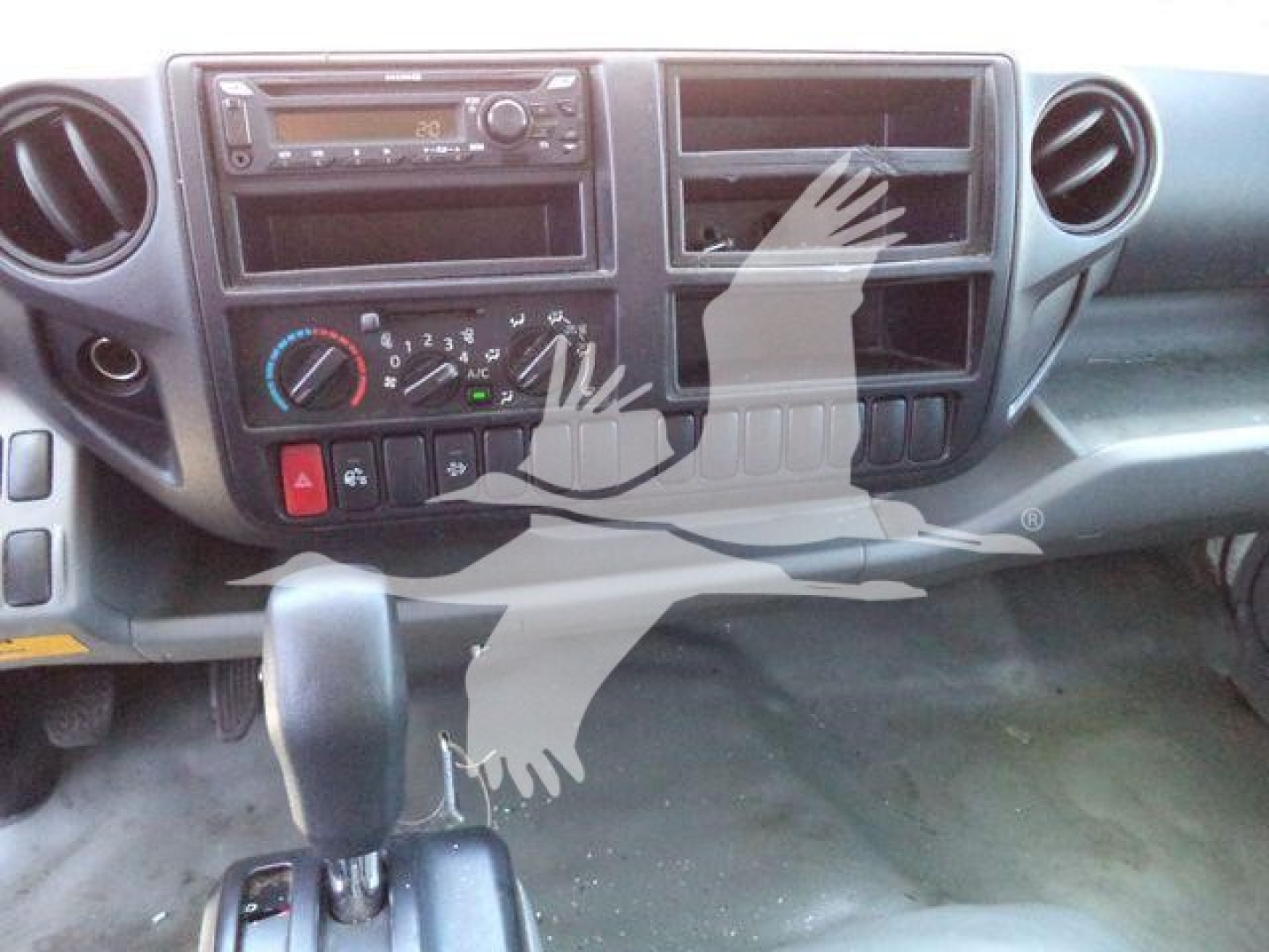Dashboard view of a 2020 Hino 195 dump truck interior showing climate controls, radio, and gear shifter.