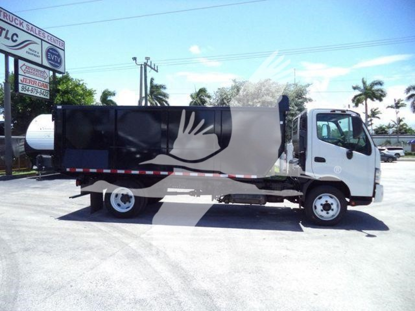 Dump truck showing side view with graphic hand logo, cab on right, black and gray body panels.