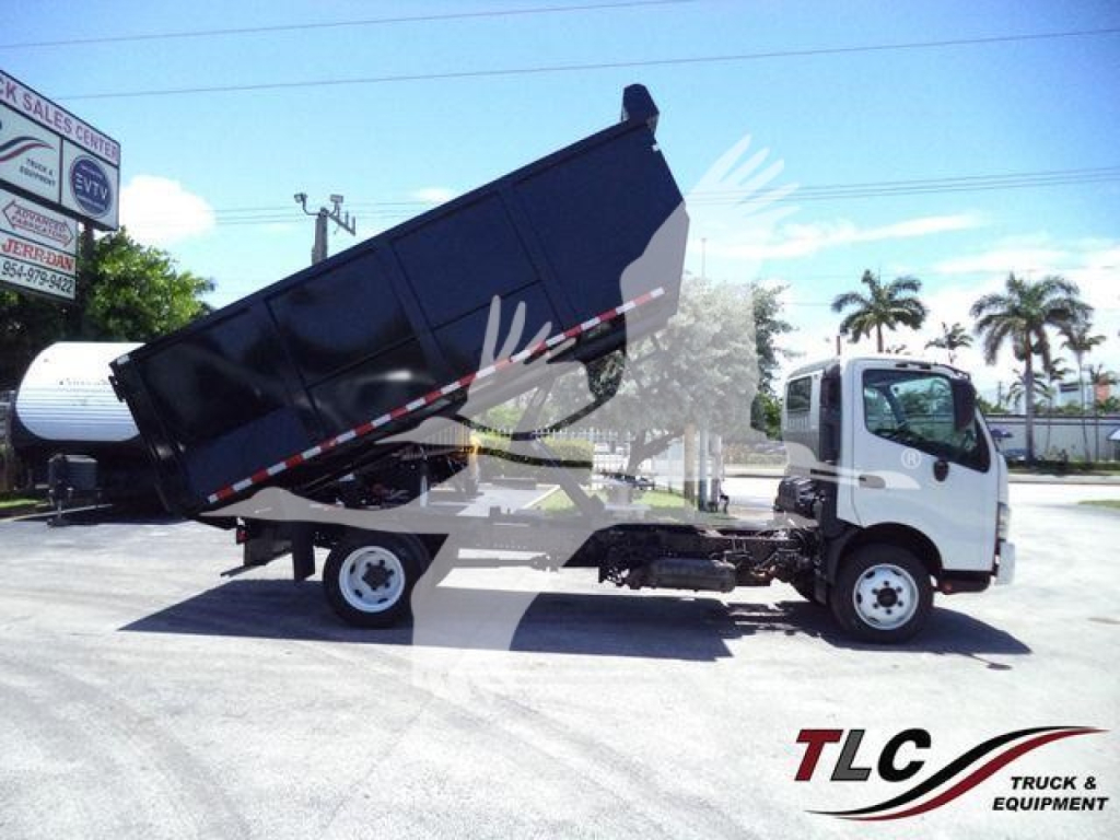 Dump truck cab and dump bed in raised position showing dump truck with white cab and black bed.