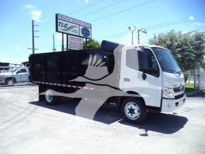 Dump truck body on a white 2020 Hino 195 with black dump bed, side view, dealership lot in background.