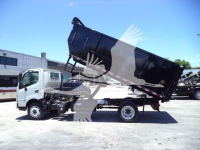 Hino 195 dump truck in-service showing side view of white cab and tilted black dump bed with hydraulic cylinder visible.
