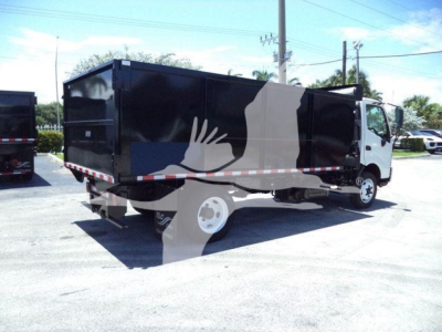 Dump truck with black dump body and white cab, side view, with reflective tape along the lower edge.