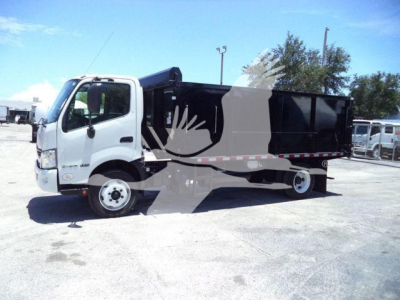 Dump truck with white cab and black dump body, side view showing cargo bed and wheels.