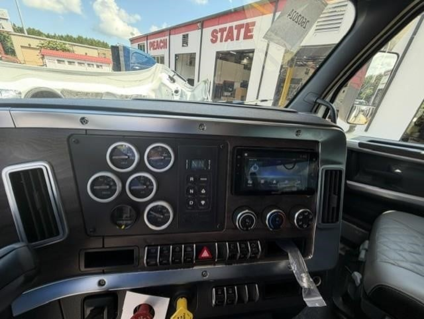 Dashboard of a Western Star 47X interior showing round analog gauges, control switches, and a touchscreen display panel.