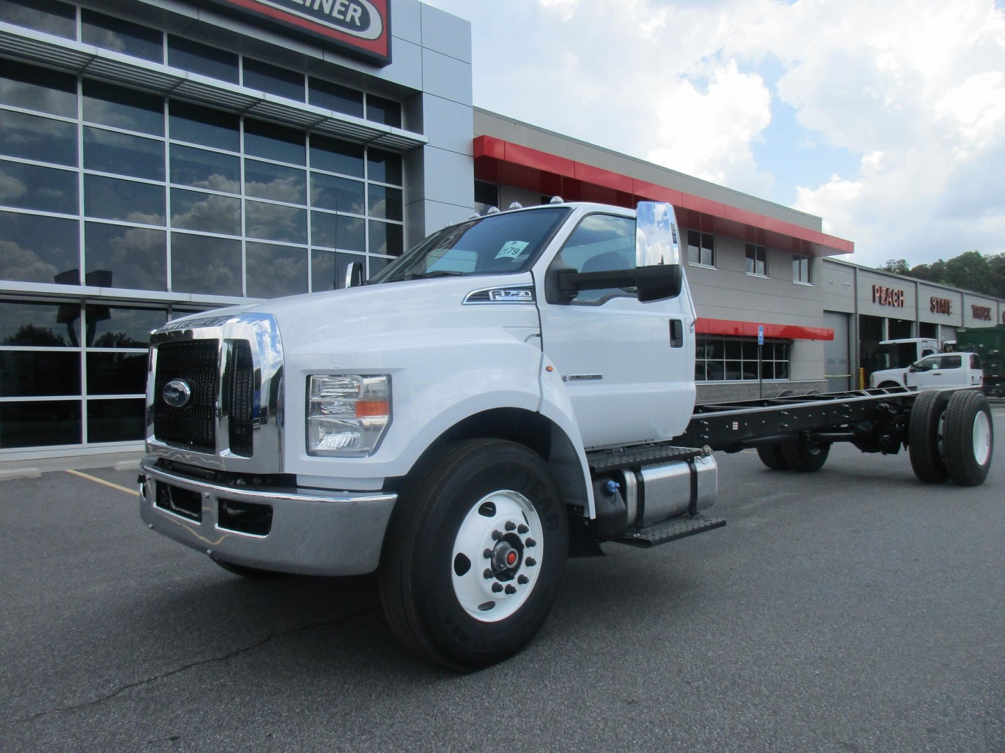2027 Ford F750 Cab and Chassis showing white truck with flatbed rear, front grille and headlights visible.